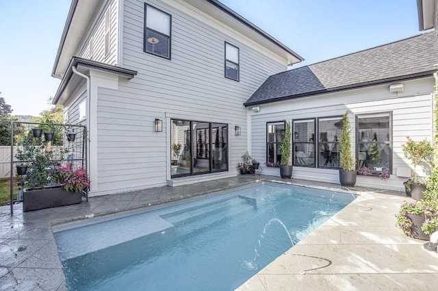 rear view of house featuring a fenced in pool and a patio area