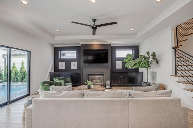 living room featuring ornamental molding, light wood-type flooring, ceiling fan, and a healthy amount of sunlight