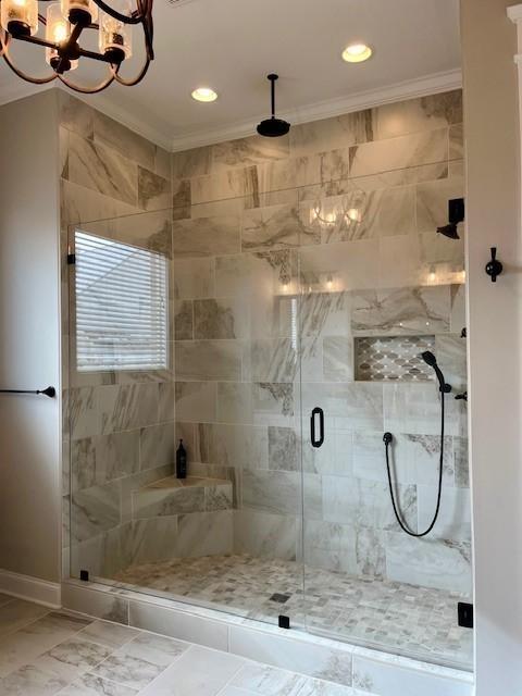 bathroom with ornamental molding, a chandelier, and walk in shower