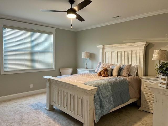 carpeted bedroom with ceiling fan and crown molding