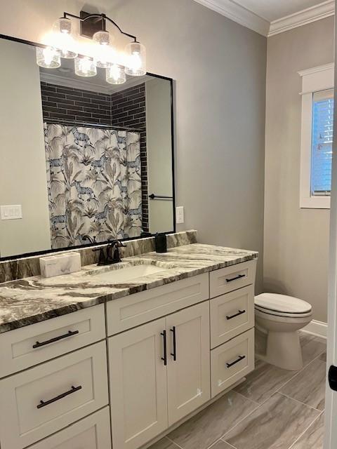 bathroom with toilet, vanity, ornamental molding, and a shower with shower curtain