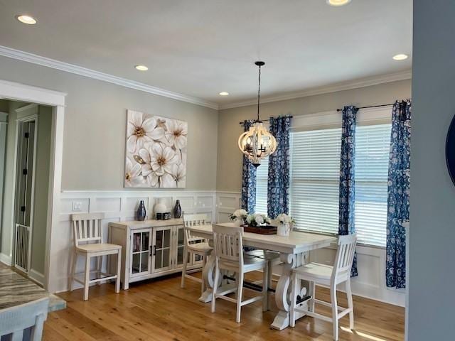 dining room with hardwood / wood-style floors, crown molding, a wealth of natural light, and a chandelier