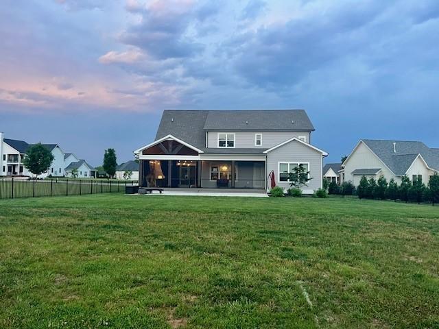 back house at dusk featuring a lawn