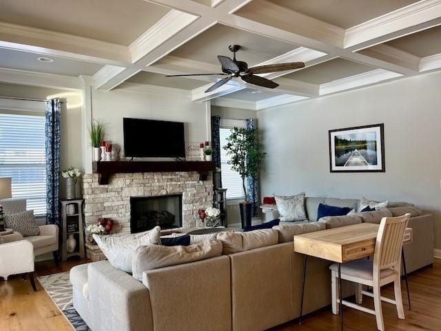 living room with coffered ceiling, a stone fireplace, beamed ceiling, crown molding, and wood-type flooring