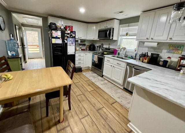 kitchen featuring sink, stainless steel appliances, decorative backsplash, white cabinets, and light wood-type flooring