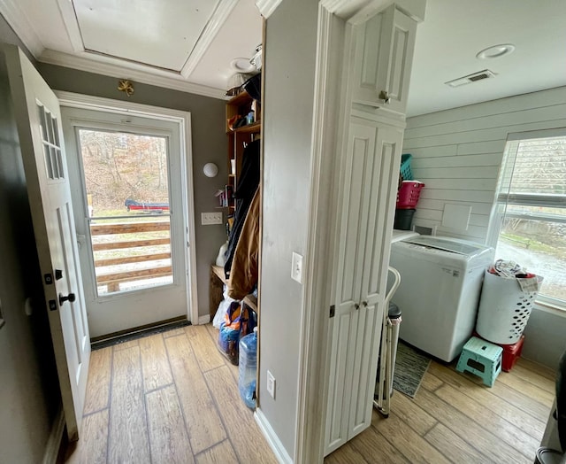 clothes washing area featuring wood walls, light wood-type flooring, and ornamental molding