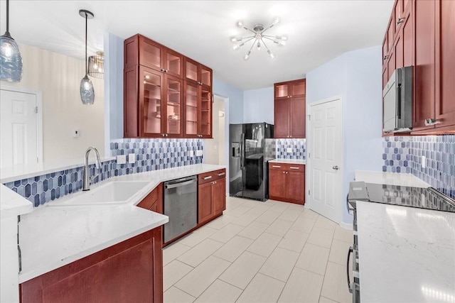 kitchen featuring light stone countertops, sink, stainless steel appliances, tasteful backsplash, and decorative light fixtures