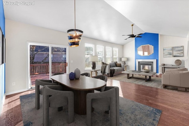 dining space with wood-type flooring, ceiling fan with notable chandelier, and vaulted ceiling