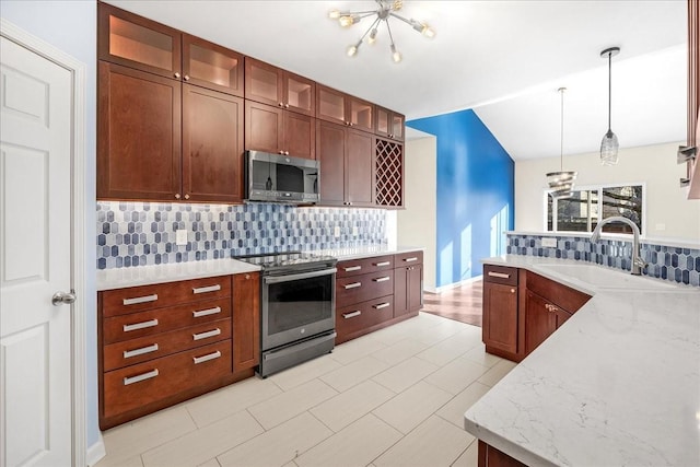 kitchen with hanging light fixtures, sink, decorative backsplash, appliances with stainless steel finishes, and light stone counters