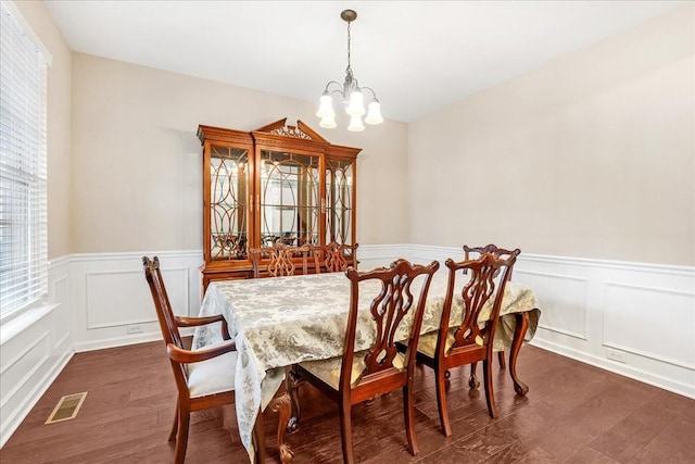 dining space with plenty of natural light, dark wood-type flooring, and an inviting chandelier