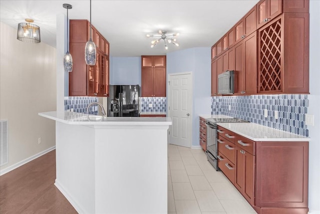 kitchen with stainless steel electric stove, black fridge, tasteful backsplash, and pendant lighting