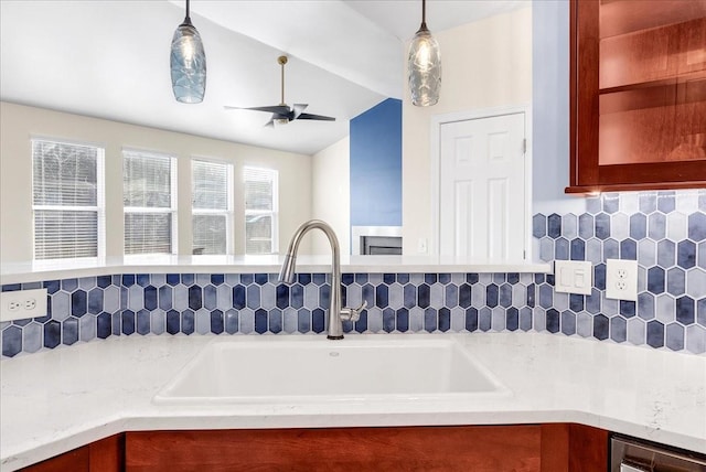 kitchen featuring tasteful backsplash, ceiling fan, sink, and pendant lighting