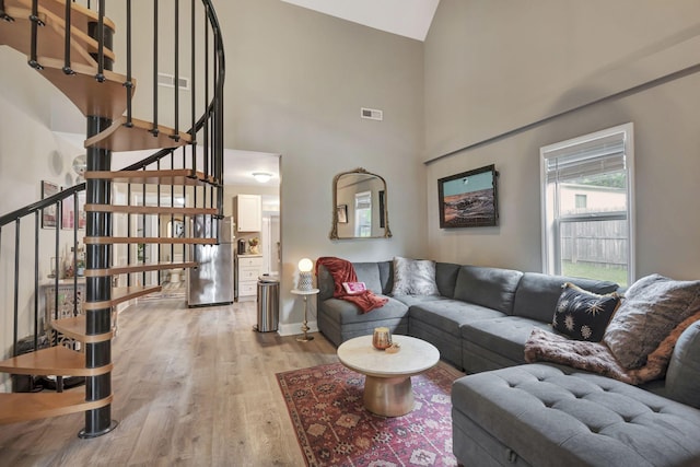 living room with light wood-type flooring and high vaulted ceiling