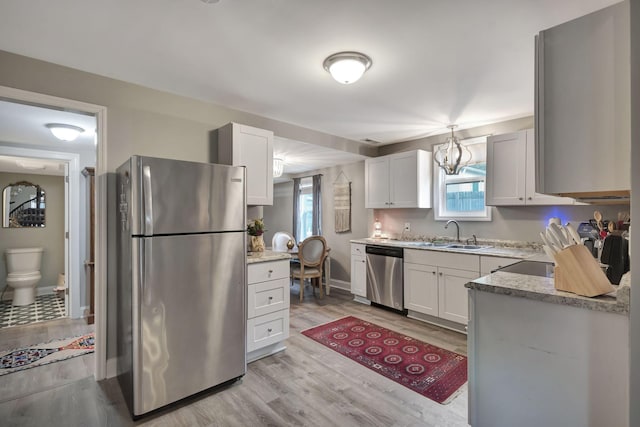 kitchen with white cabinetry, sink, light hardwood / wood-style flooring, and appliances with stainless steel finishes