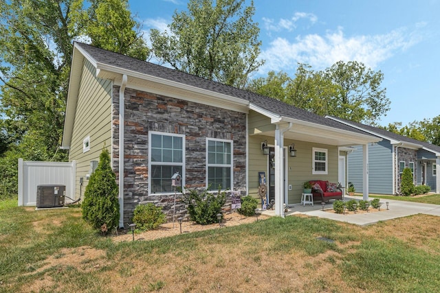 ranch-style house featuring a porch, central air condition unit, and a front yard