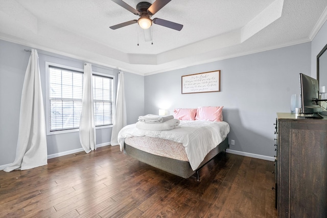 bedroom with ceiling fan, dark hardwood / wood-style floors, a raised ceiling, and crown molding