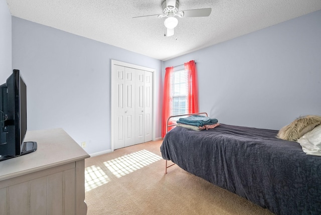 carpeted bedroom with a textured ceiling, a closet, and ceiling fan