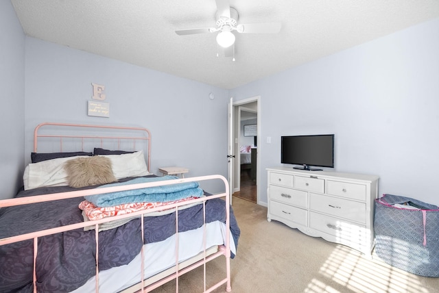 bedroom featuring light carpet, a textured ceiling, and ceiling fan