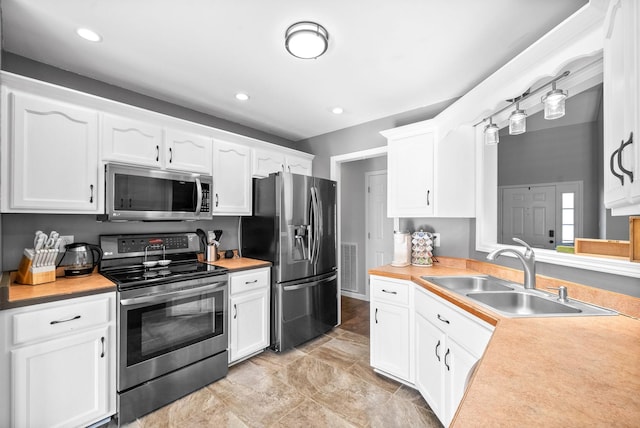 kitchen featuring stainless steel appliances, white cabinetry, and sink