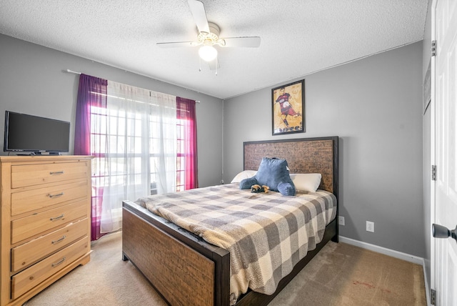 carpeted bedroom featuring ceiling fan and a textured ceiling