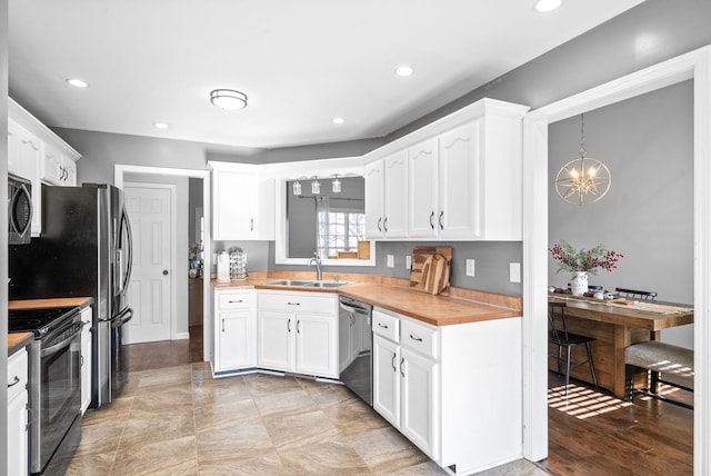 kitchen featuring dishwasher, sink, black electric range oven, pendant lighting, and white cabinets