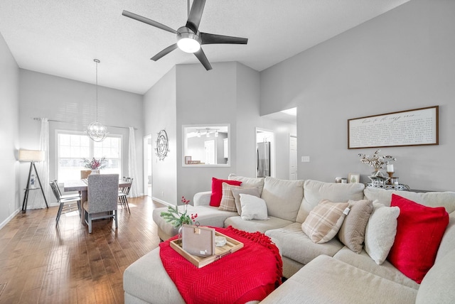 living room featuring a textured ceiling, high vaulted ceiling, wood-type flooring, and ceiling fan with notable chandelier