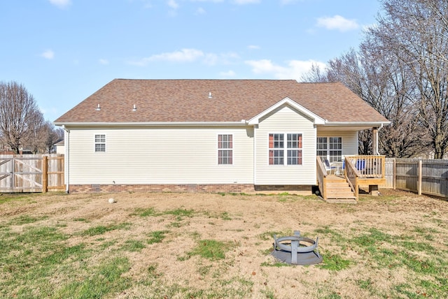 rear view of house with a fire pit, a deck, and a yard