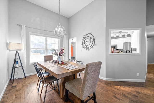 dining room with dark hardwood / wood-style flooring, a towering ceiling, and a chandelier