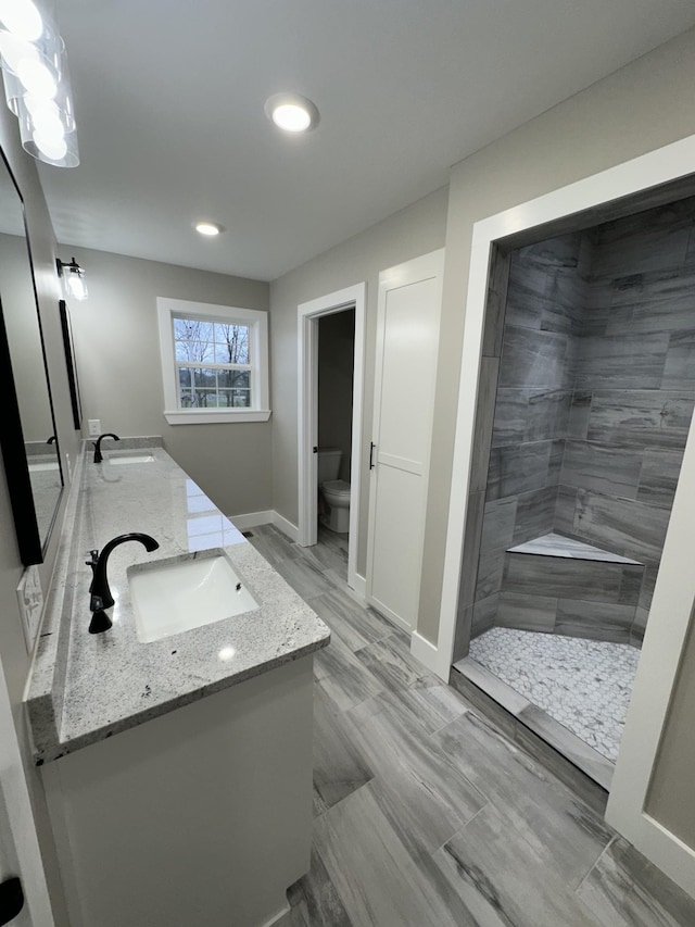 bathroom featuring tiled shower, vanity, and toilet