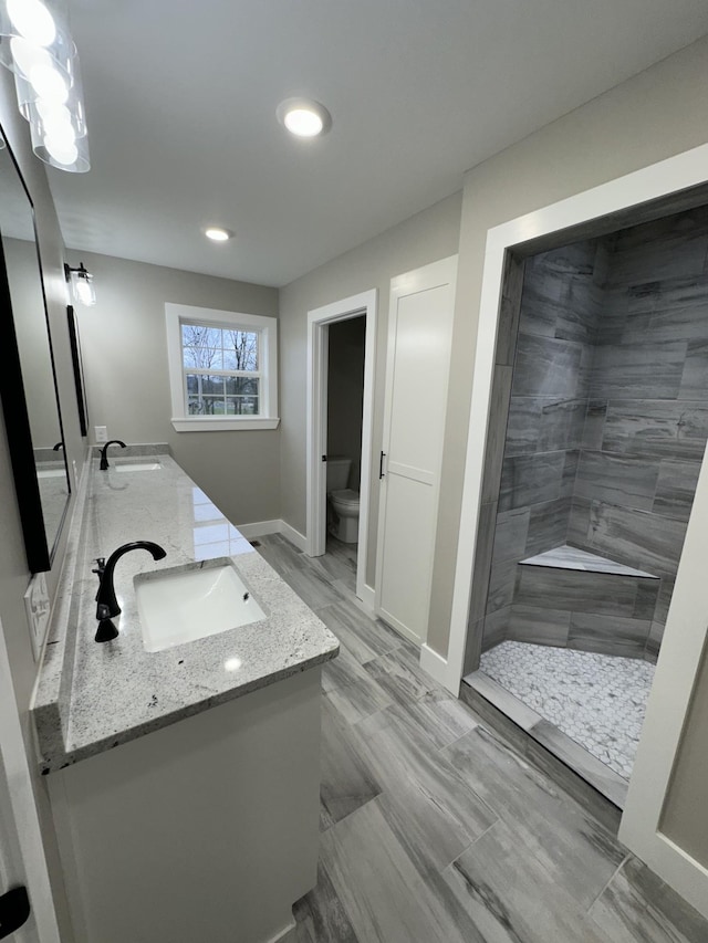 bathroom featuring a tile shower, vanity, and toilet