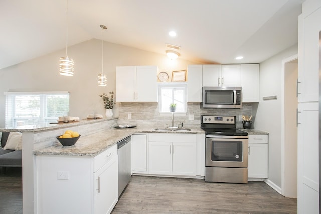 kitchen with sink, stainless steel appliances, kitchen peninsula, vaulted ceiling, and white cabinets