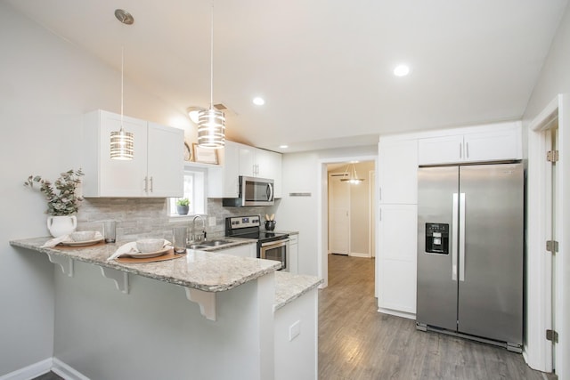 kitchen featuring backsplash, white cabinets, decorative light fixtures, kitchen peninsula, and stainless steel appliances