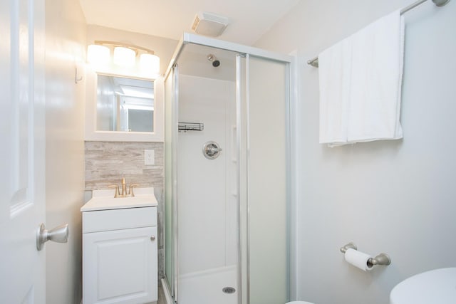 bathroom featuring decorative backsplash, toilet, a shower with door, and vanity