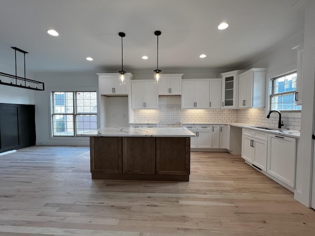 kitchen featuring a center island, white cabinets, decorative light fixtures, and sink