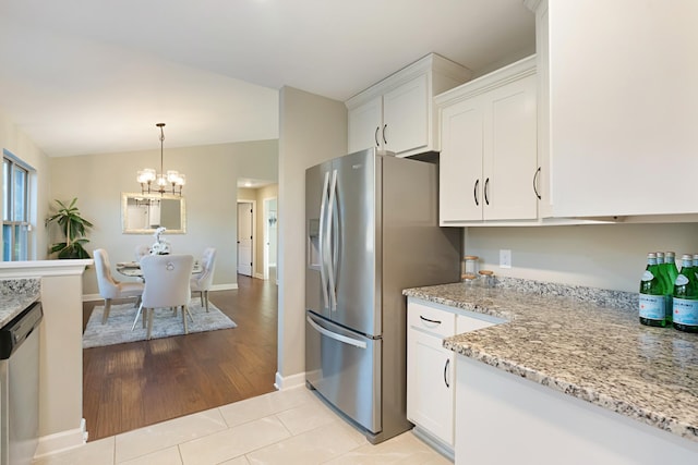 kitchen featuring light stone countertops, appliances with stainless steel finishes, light tile patterned flooring, white cabinetry, and a chandelier