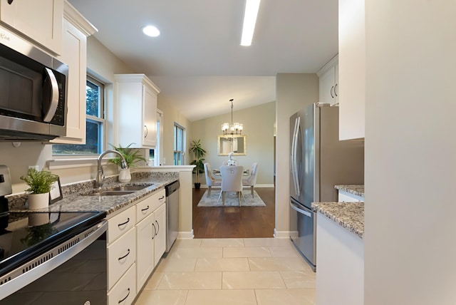 kitchen featuring sink, white cabinetry, stainless steel appliances, and vaulted ceiling