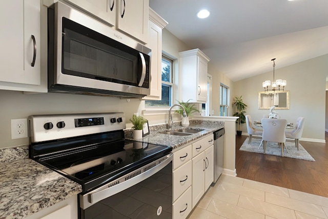 kitchen with stainless steel appliances, sink, a chandelier, white cabinetry, and lofted ceiling