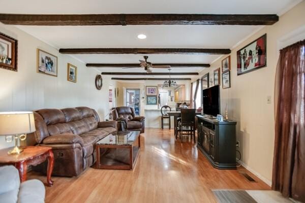 living room with ceiling fan, beamed ceiling, and light hardwood / wood-style floors