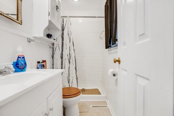 bathroom with tile patterned floors, curtained shower, vanity, and toilet