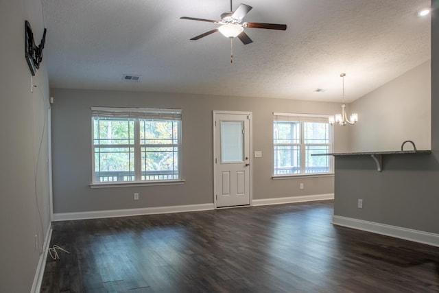 unfurnished living room with a textured ceiling, lofted ceiling, ceiling fan with notable chandelier, and dark hardwood / wood-style floors