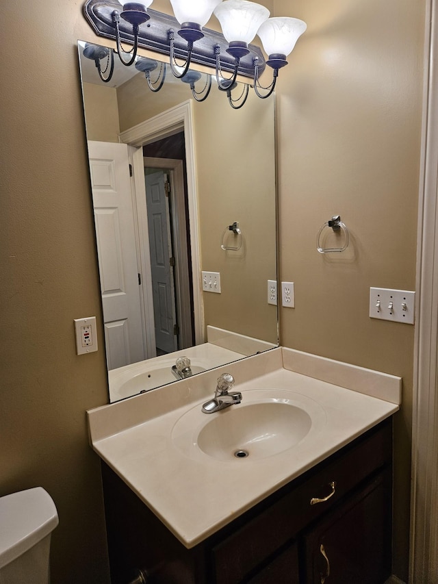 bathroom featuring vanity, toilet, and a notable chandelier