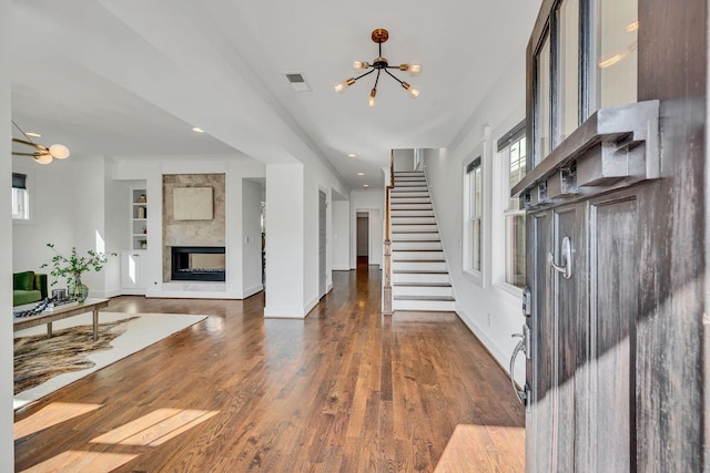 entrance foyer featuring a multi sided fireplace, dark hardwood / wood-style flooring, and a chandelier