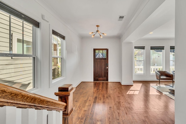 entrance foyer with crown molding, hardwood / wood-style floors, and an inviting chandelier