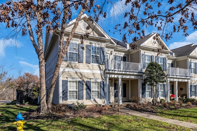 view of front of property featuring a balcony and a front yard