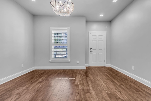 spare room featuring wood-type flooring and a notable chandelier