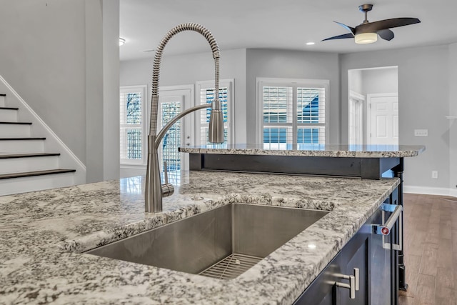 kitchen with light stone countertops, ceiling fan, a healthy amount of sunlight, and sink