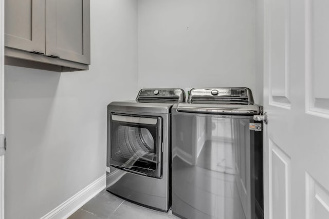 washroom with cabinets, light tile patterned floors, and washer and dryer