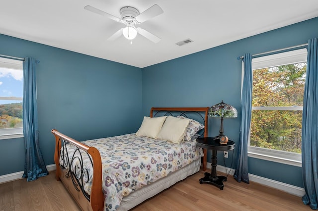 bedroom featuring multiple windows, light hardwood / wood-style floors, and ceiling fan