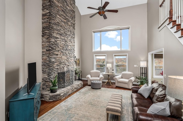 living room featuring a wood stove, ceiling fan, hardwood / wood-style floors, and high vaulted ceiling