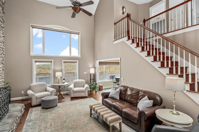 living room with ceiling fan, wood-type flooring, and a high ceiling